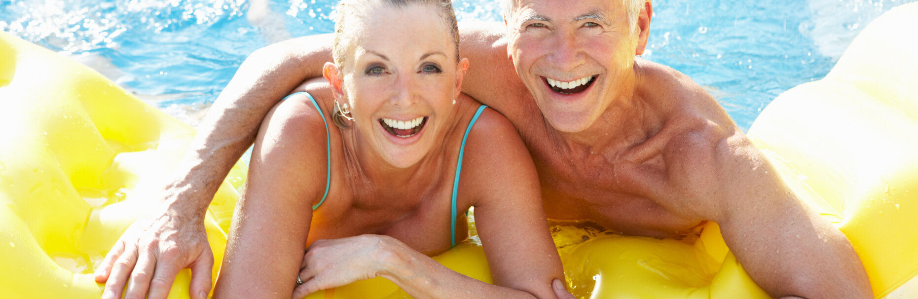 Bezpieczne wakacje – uśmiechnięta para starszych osób w basenie